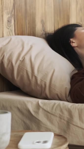 ベッドに横たわっている無視された白人女性は,携帯電話のメッセージから目を覚ます. オンラインテキスト,ニュースを読む. 目覚めるコンセプト。 バーティカルビデオ. - 映像、動画
