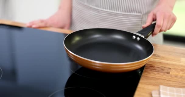 Cook putting frying pan and turning on stove closeup 4k movie slow motion. Cooking at home concept - Footage, Video