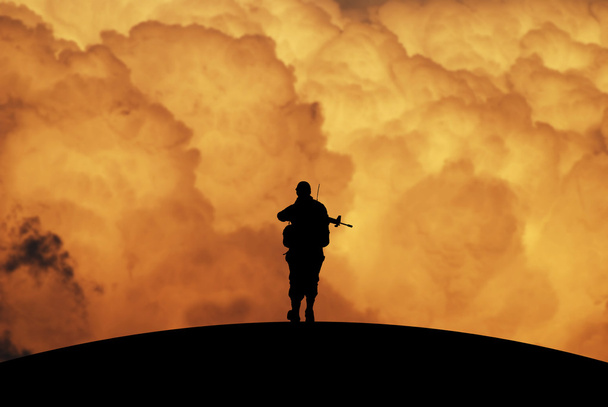 Silhouette d'un soldat solitaire au ciel dramatique à l'aube
 - Photo, image