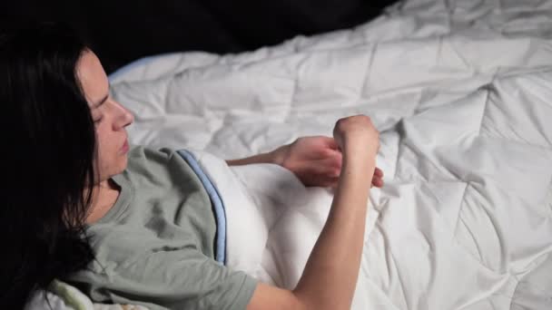 Junge Frau unter weicher Decke auf Licht, Bett nimmt nachdenklich Tabletten mit einer Hand und Glas Wasser in andere Pflege und Erholung, Konzept für Beschreibungen konzentriert sich auf Momente der persönlichen Gesundheit  - Filmmaterial, Video
