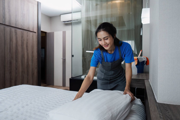 cleaning service woman worker clean bedroom at home. housekeeper cleaner feel happy and make bed look neat. housework and housekeeping cleaning service. - Photo, Image