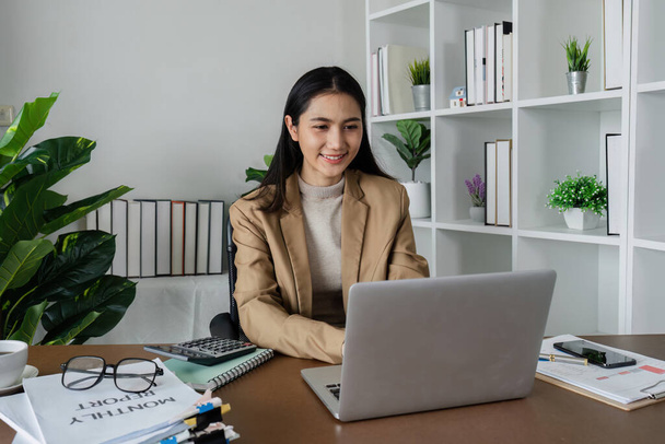empresaria en la oficina usando el ordenador portátil en el trabajo, sonriente ejecutiva de la compañía femenina profesional usando traje de trabajo en la computadora en el lugar de trabajo. - Foto, imagen