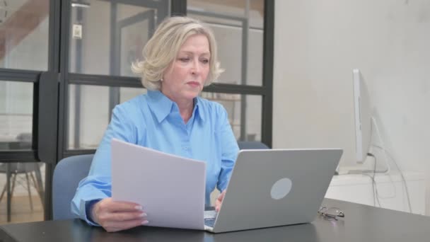 Napjaté starší žena pocit neklidu pro práci na notebooku a dokumenty - Záběry, video