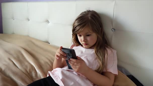 Söpö esiteini tyttö käyttää älypuhelinta kotona, hidastettuna. Laadukas 4k kuvamateriaalia - Materiaali, video