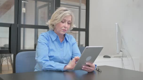 Starší stará žena pracující na digitálním tabletu - Záběry, video