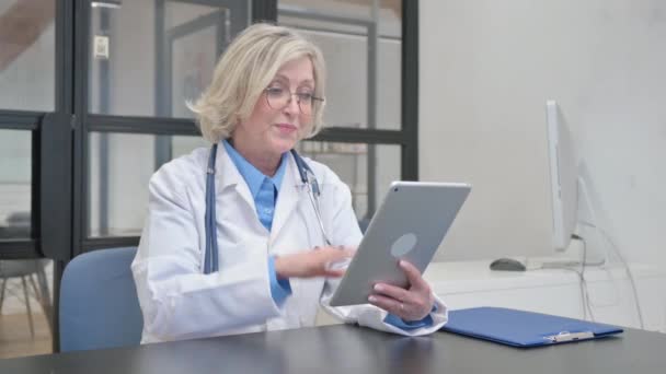 Senior vrouwelijke arts doet video Chat op tablet in het ziekenhuis - Video
