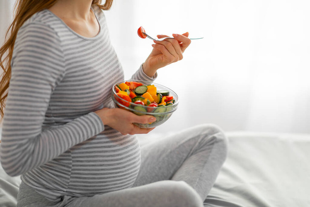 Hamile bir kadının sağlıklı bir salataya düşkünlüğünü fotoğraflıyor ve hamile anneler için beslenme düzeninin önemini vurguluyor. - Fotoğraf, Görsel