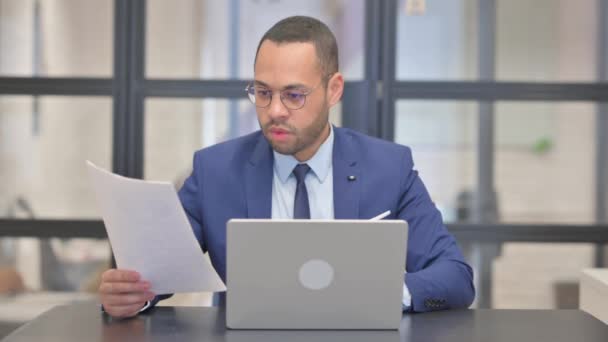 Mixed Race Businessman Celebrating Success while Working Laptop and Documents - Footage, Video