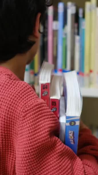 Malý chlapec vybírá knihy v knihovně - Záběry, video