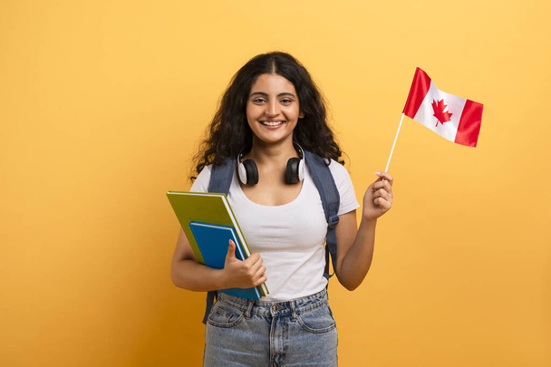 Χαρούμενος νεαρός μαθητής που επιδεικνύει καναδική σημαία, αντιπροσωπεύοντας υπερηφάνεια και πολιτιστική ταυτότητα - Φωτογραφία, εικόνα