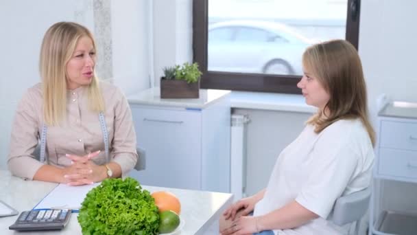 A nutritionist consults with a patient about diet and nutrition in a well-lit office. - Footage, Video