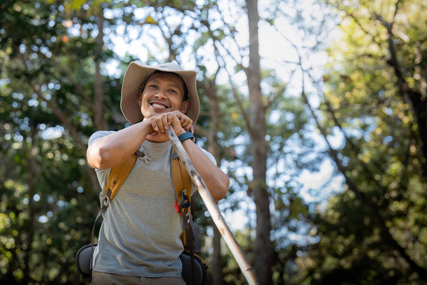 Nuori mies aasialainen vaellus puiden keskellä reppu, nuori mies nauttia yksin metsässä. Retkeily, vaellus, matkustaminen, seikkailukonseptin etsiminen. - Valokuva, kuva