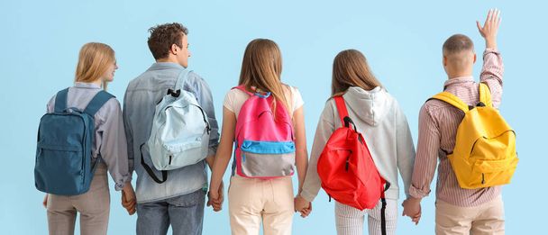 Group of students with backpacks on light blue background, back view - Photo, Image