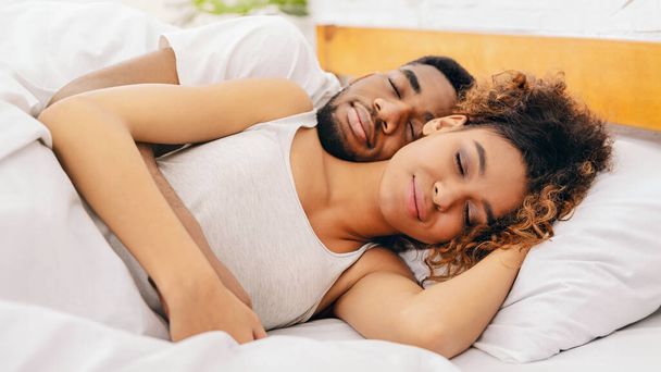 Απαλή εικόνα του Αφροαμερικανού ζευγαριού να αγκαλιάζεται στον ύπνο, δείχνοντας αγάπη και εμπιστοσύνη σε μια σχέση σε μια γαλήνια στιγμή - Φωτογραφία, εικόνα