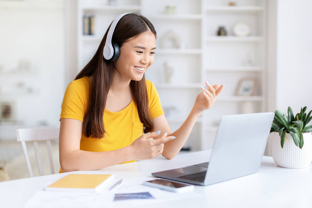 Młoda azjatycka kobieta swobodnie ubrana w słuchawki na laptopie do rozmowy wideo, student ma lekcje online - Zdjęcie, obraz