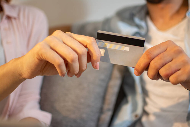 Zbliżenie męskich i żeńskich rąk trzymających kartę bankową razem. Mężczyzna i kobieta trzymający kartę kredytową razem. - Zdjęcie, obraz