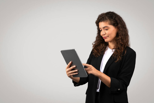 Donna d'affari impegnata con un tablet digitale, possibilmente rivedere i rapporti o la navigazione - Foto, immagini