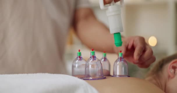 Masseur, cupping therapy and back of person in spa for treatment, body or muscle pain with vacuum cups. Massage or therapist, client and skincare with jar for health, wellness and relax or rest. - Footage, Video