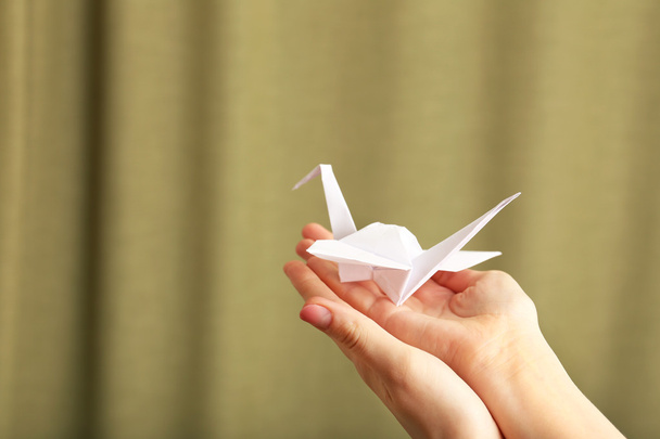 Female hand with paper crane on blurred background - Фото, изображение