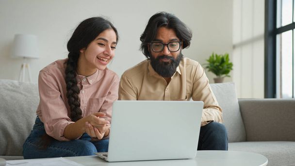 Gülümseyen Arap iş adamı çift Müslüman kadın görüntülü konuşma webcam laptop konferansı ev ofisindeki çok ırklı erkek kız arkadaş canlısı sanal sohbet karantinada gülüşmeler - Fotoğraf, Görsel