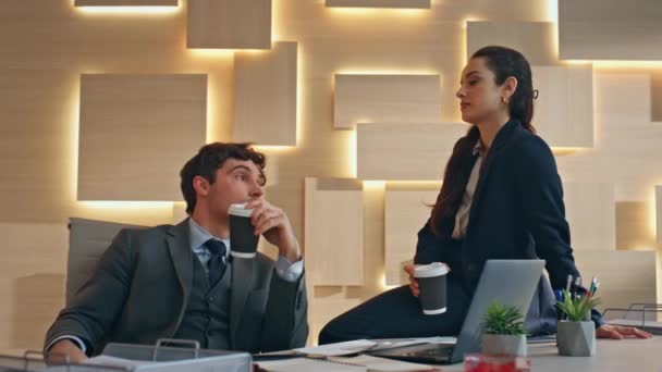 Obchodní pár pije kávu mluvit ve večerní kanceláři detailní. Uvolnění firemní pracovníci si užívají odpočinkovou kancelář s cappuccinem v béžovém kabinetu. Kolegové partneři v neformální atmosféře - Záběry, video