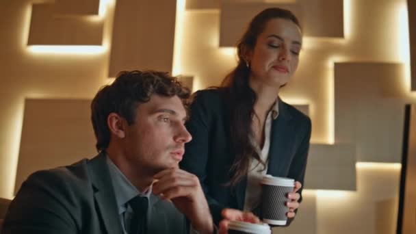 Woman assistant bringing coffee to boss at evening cabinet closeup. Two focused office employees discussing project. Ceo businessman working computer asking lady. Business partners teamwork concept - Footage, Video