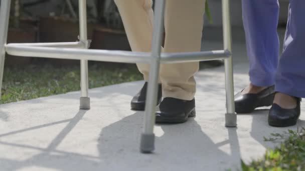 Elderly woman exercise walking in backyard with caregiver. - Metraje, vídeo