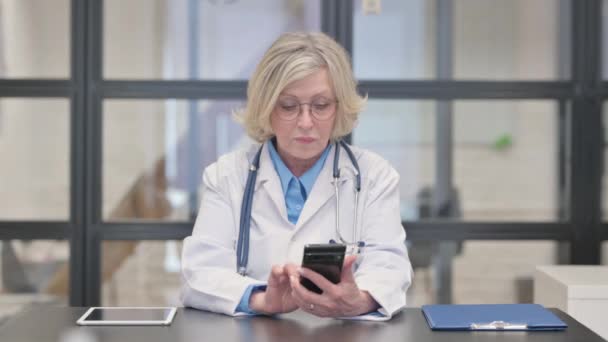 Stara kobieta lekarz przeglądanie Internetu na smartfonie - Materiał filmowy, wideo