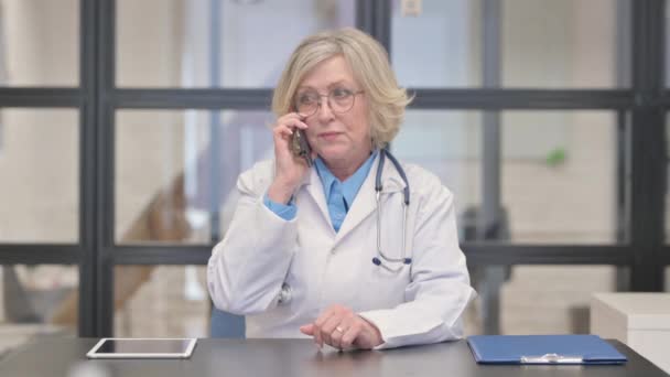 Stará žena lékař mluví na telefonu s pacientem - Záběry, video