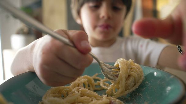 Çocuk spagetti yiyor, yemek zamanı, 5 yaşında karbonhidrat zengini bir çocuğun yakın plan yüzü. - Fotoğraf, Görsel
