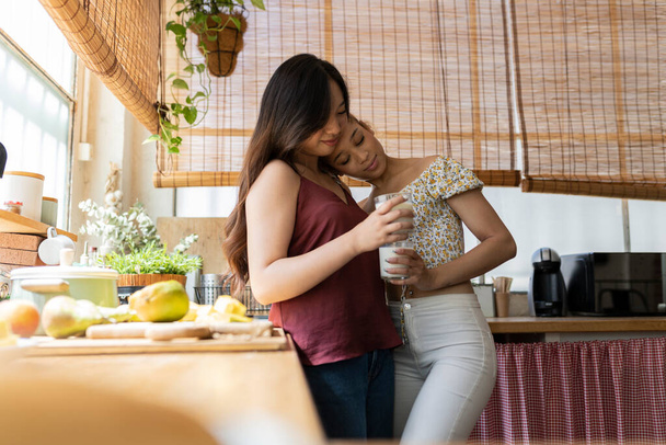 Un tenero abbraccio è condiviso tra due amici in una cucina baciata dal sole, creando un quadro di calore e affetto. - Foto, immagini