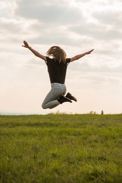 щасливі молоду жінку, перестрибуючи через Синє небо - Фото, зображення
