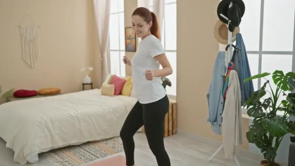 Μια νεαρή λευκή γυναίκα χορεύει χαρούμενα στο άνετο δωμάτιό της, αποπνέοντας ευτυχία και ενέργεια.. - Πλάνα, βίντεο