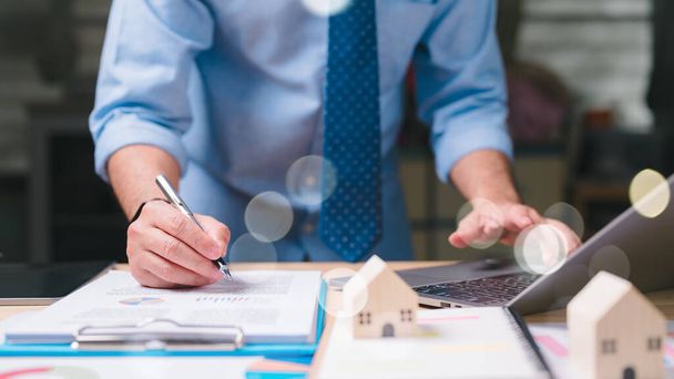 Фінансовий менеджер пише на аркуші паперу ручкою. На синій сорочці і блакитній краватці. Концепція професіоналізму і зосередження, як людина займається завданням, яке вимагає концентрації - Фото, зображення