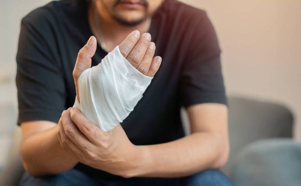 Man with a gauze bandage wrapped around his hand. First aid, accident and injury treatment concept. Selective focus. - Photo, Image
