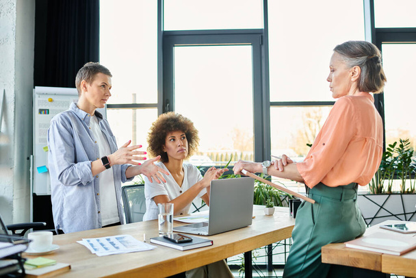 Een groep hardwerkende, diverse zakenvrouwen zitten rond een tafel, werken samen in een kantooromgeving. - Foto, afbeelding