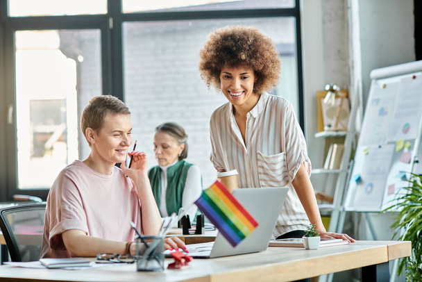 Привлекательные разнообразные деловые женщины, работающие вместе над проектом в офисе, флаг гордости. - Фото, изображение