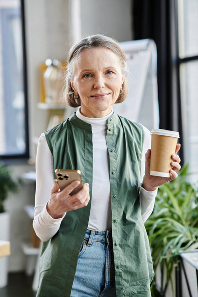Businesswoman holds coffee cup and phone. - Photo, Image