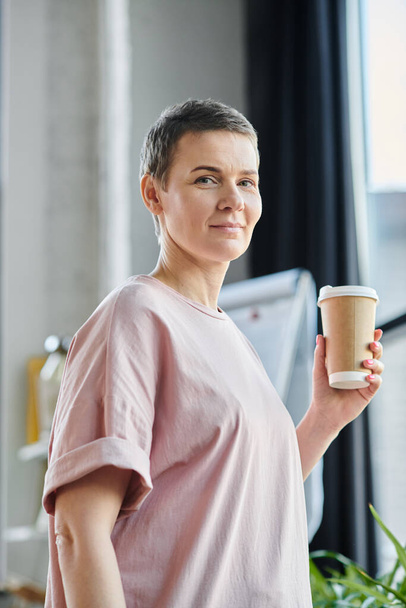 Uma mulher de camisa rosa saboreia uma xícara de café. - Foto, Imagem
