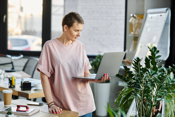 Houkutteleva nainen, kirkkaan vaaleanpunainen paita, toimii ahkerasti kannettavalla tietokoneella. - Valokuva, kuva
