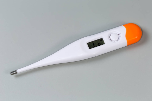 Elektronisches klinisches Thermometer mit LCD-Anzeige zur Messung liegt auf einer grauen Oberfläche, Nahaufnahme - Foto, Bild
