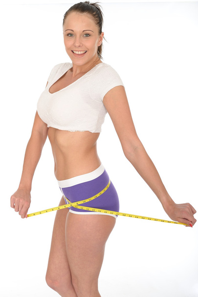 Mujer joven y saludable revisando su pérdida de peso con una cinta métrica
 - Foto, Imagen
