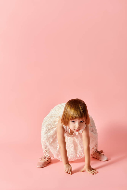 Kleines Mädchen im weißen Kleid posiert in Bewegung auf rosa Hintergrund. - Foto, Bild