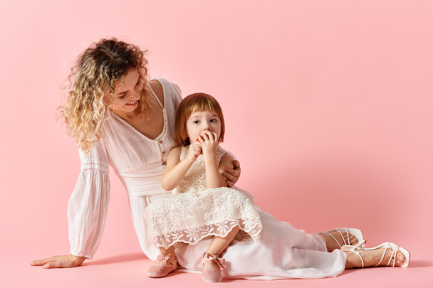 Mother and daughter in embrace on a soft pink background. - Photo, Image