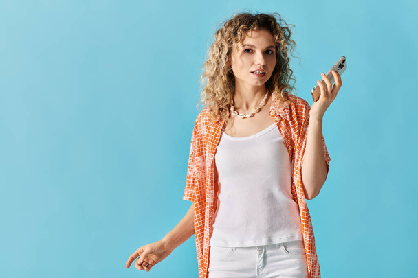 Curly-haired beauty holding smartphone gracefully. - Photo, Image