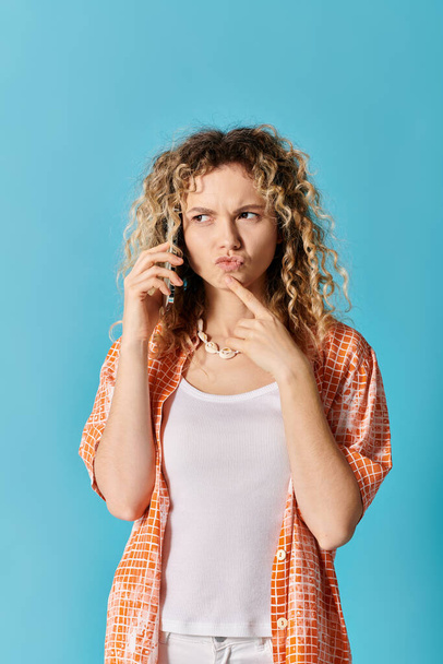 Mladá žena s kudrnaté vlasy mluví na mobilním telefonu proti barevné pozadí. - Fotografie, Obrázek