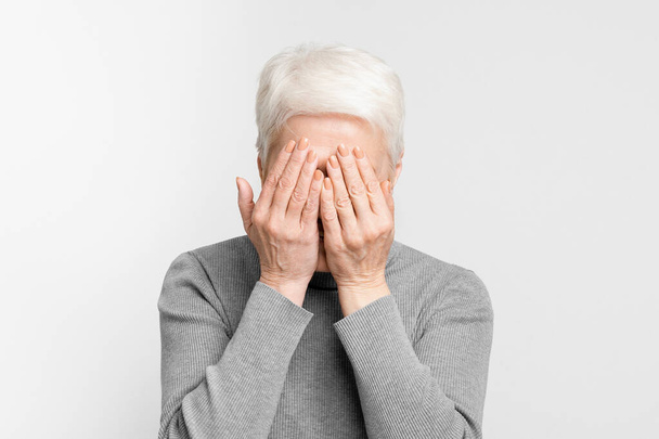 Kuva vanhuksesta eurooppalaisesta naisesta, joka kätkee identiteettinsä käsillään, vetoaa yksityisyyden tunteeseen, mysteereihin ja elämänkokemuksiin - Valokuva, kuva