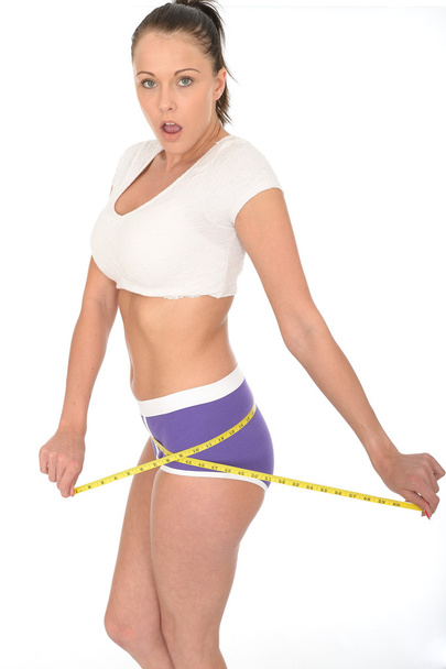 Здоровая молодая женщина проверяет свою потерю веса с помощью ленты
 - Фото, изображение