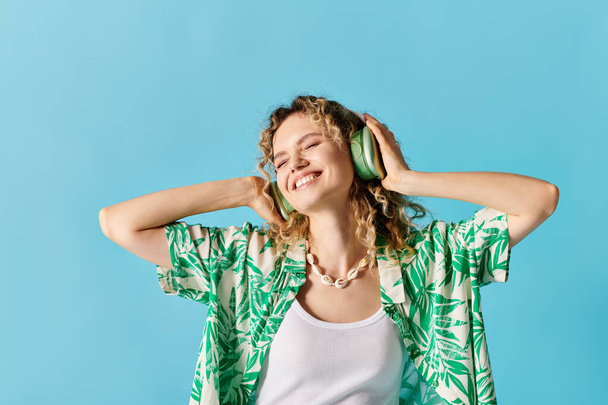 Mujer con auriculares escuchando música contra fondo azul. - Foto, imagen