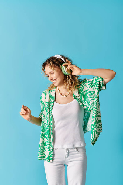 Mujer con estilo en camisa verde y pantalones blancos, escuchando música. - Foto, Imagen